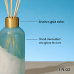 Diffuser bottle with gold collar and sea glass texture on a blue background