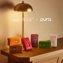 Gold lamp on a wooden surface with colorful boxes and 'capri BLUE' and 'pura' branding.