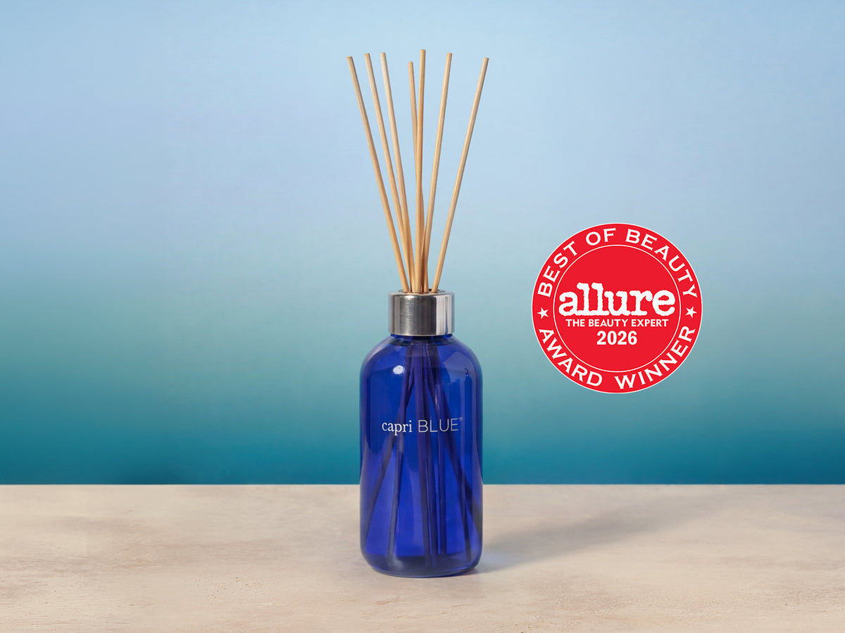 A reed diffuser bottle in cobalt blue glass with natural reed sticks beside the Allure 2026 Best of Beauty Award Winner seal.