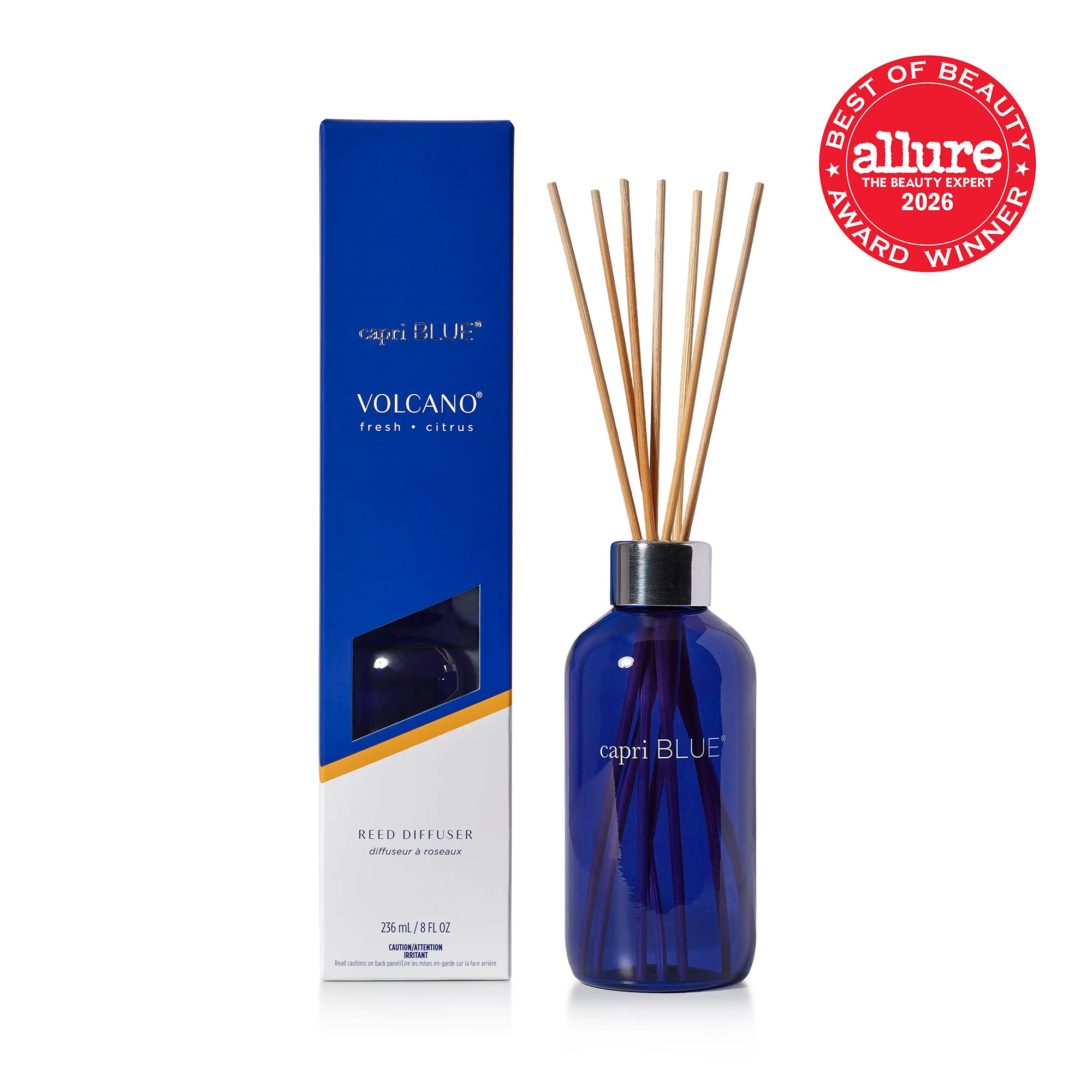 A reed diffuser bottle in cobalt blue glass with natural wood reeds and a silver collar, shown next to its  blue and white packaging box and the Allure 2026 Best of Beauty Award Winner seal.