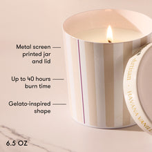 Striped candle with text detailing features on a marble surface