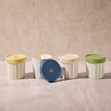 Five ice cream containers with striped patterns and colorful lids on a textured surface.