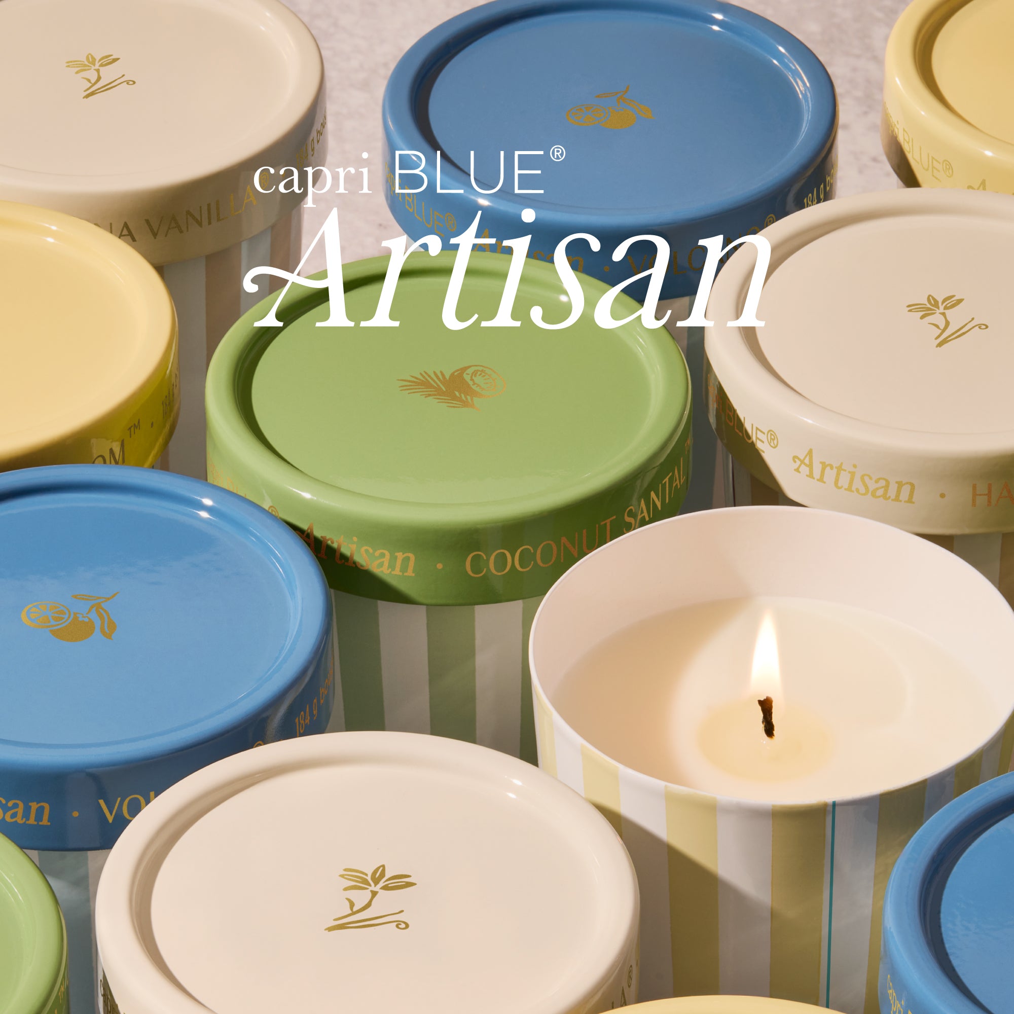 Collection of capri BLUE Artisan candles with colorful lids on a textured surface.