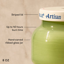 Green glass jar with a striped lid labeled 'Artisan' on a beige background.