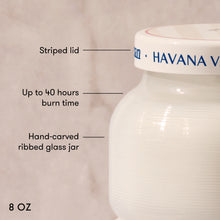 White hand-carved ribbed glass jar with striped lid labeled 'Havana V', featuring text on burn time and size.