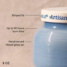 Blue Artisan candle jar with labeled features on a beige background