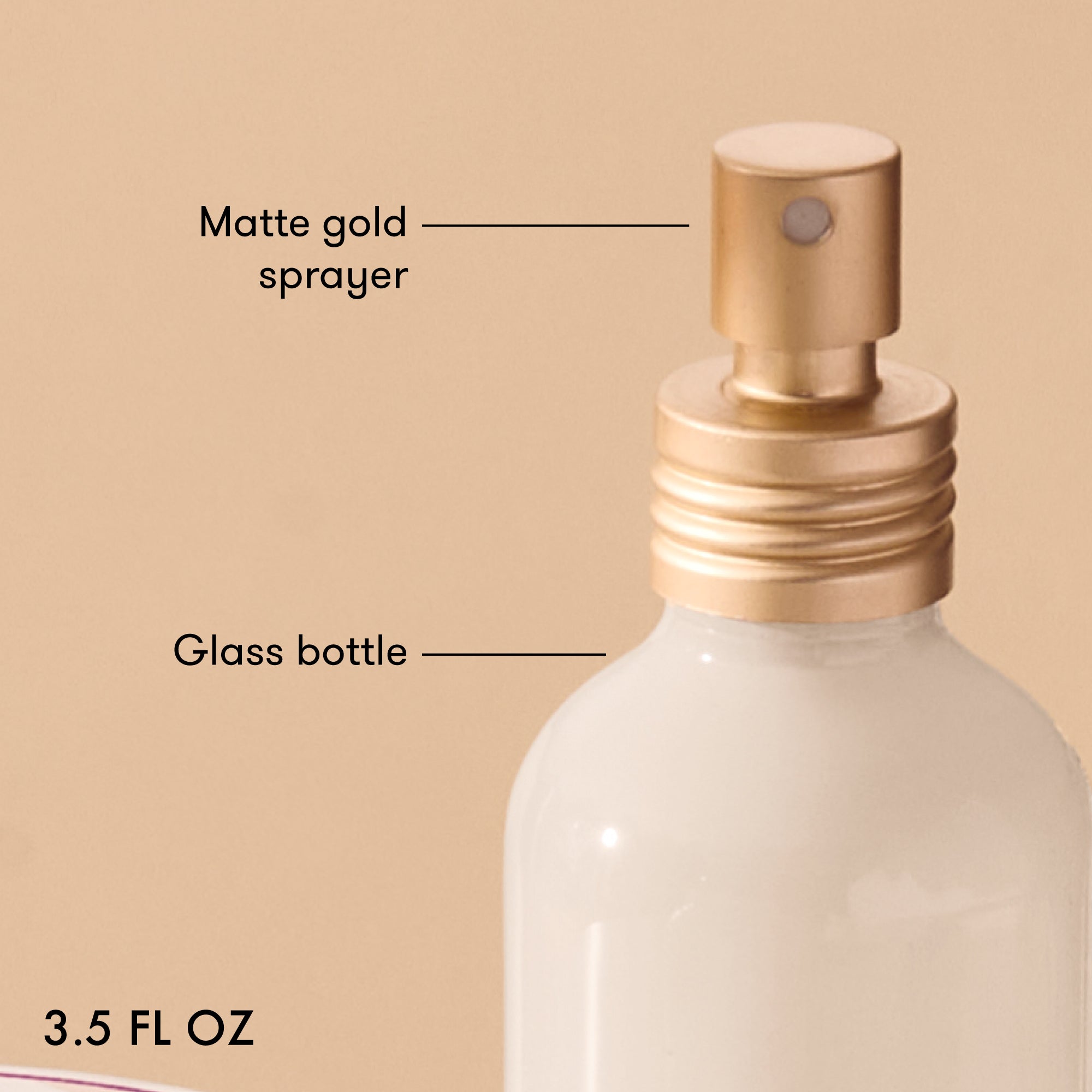 Glass bottle with matte gold sprayer labeled on a beige background