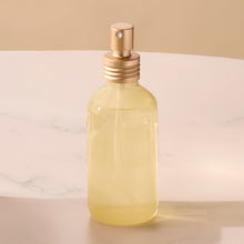 Clear glass bottle with gold cap on a beige background