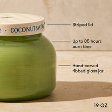 Green coconut scented candle with labeled features on a wooden surface