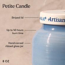 Blue candle jar with striped lid labeled 'Artisan Blue' on a beige background