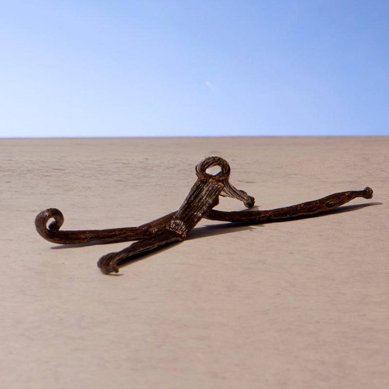 Rustic metal anchor on a sandy surface with a clear blue sky.