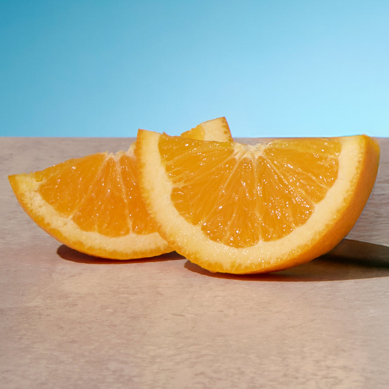 Two orange slices on a wooden surface with a blue background