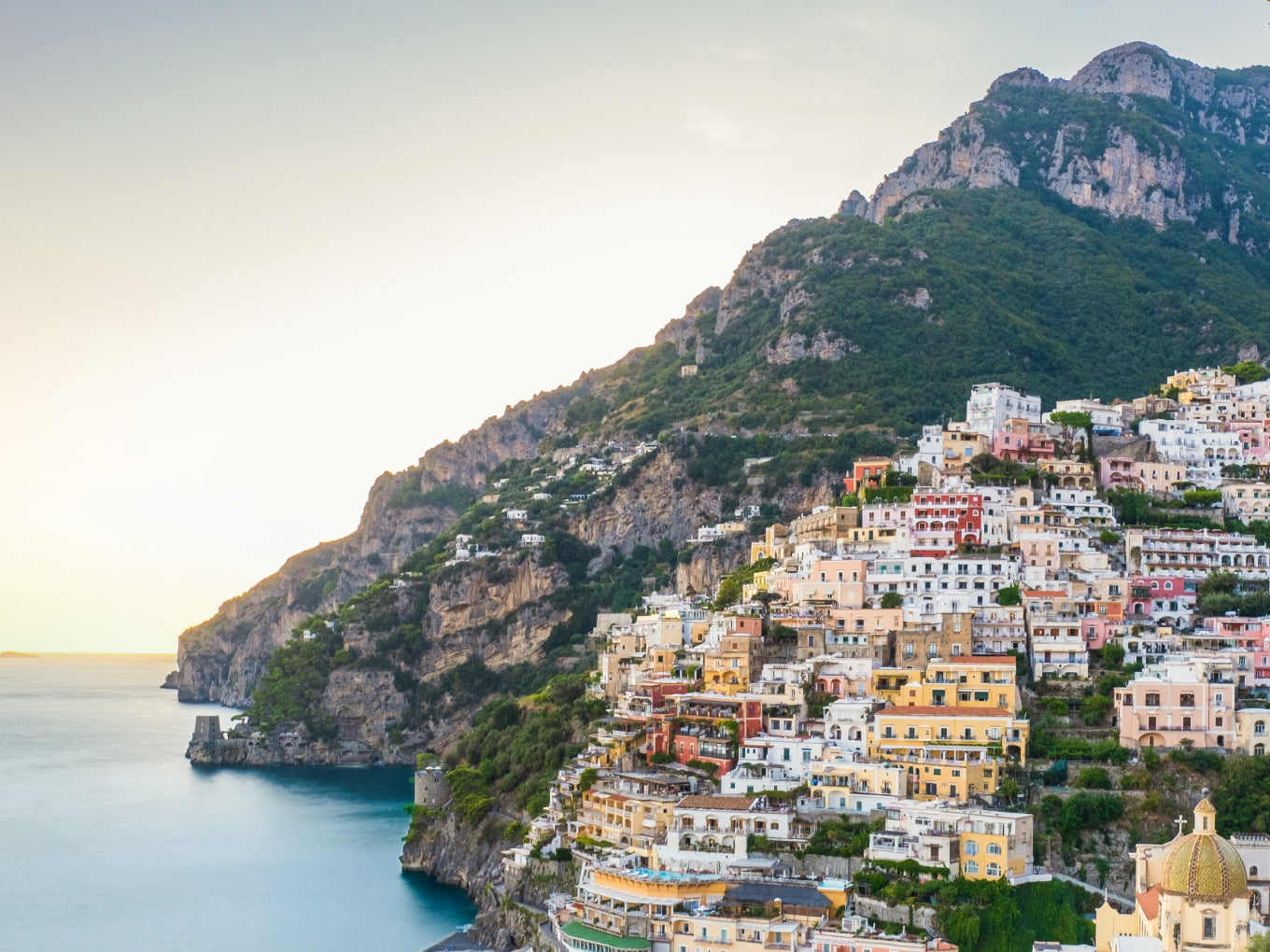 Hillside village with colorful houses overlooking the ocean and mountains.