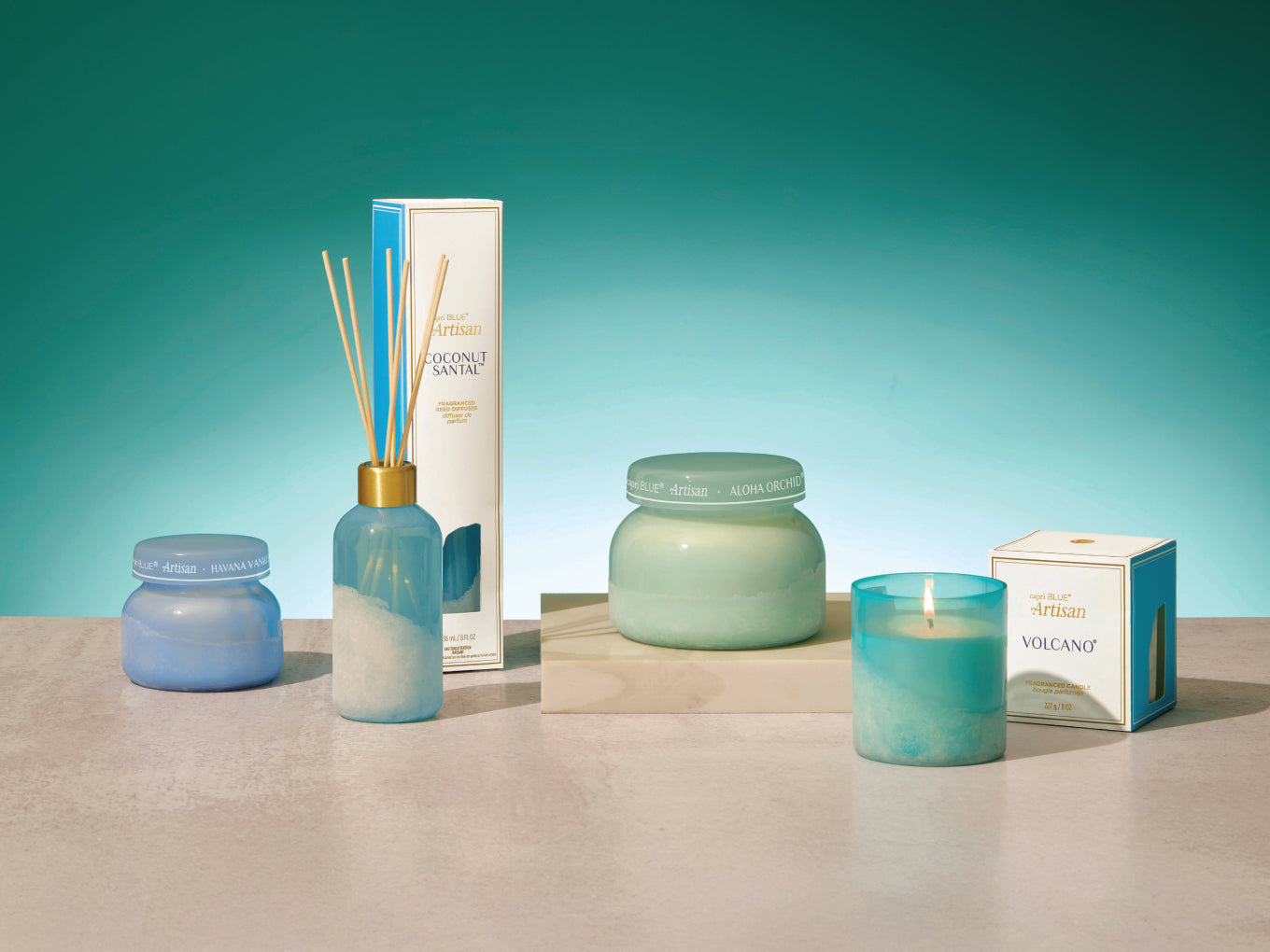 Collection of decorative items including candles and diffusers on a neutral surface with a teal background.