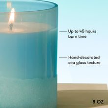 Blue glass candle with text indicating burn time and size