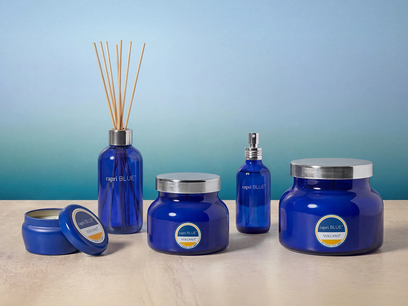 Collection of Signature Home Fragrance products like room spray, candles and diffusers on a marble surface with a blue background