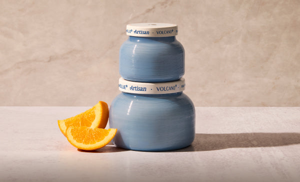 Two blue ceramic jars with white labels on a beige surface with an orange slice.