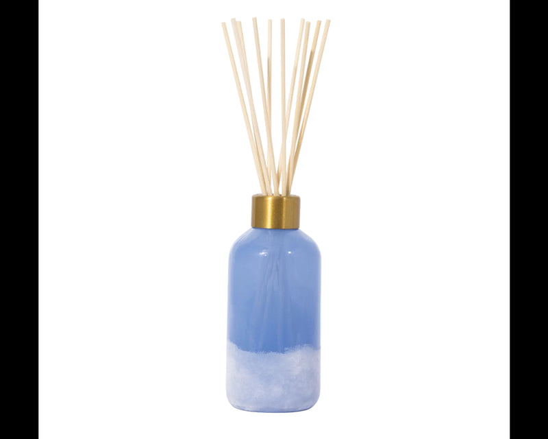 Blue diffuser bottle with gold cap and wooden sticks on a white background