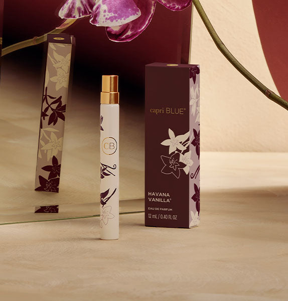 Capri Blue Havana Vanilla perfume bottle and packaging on a wooden surface with floral background