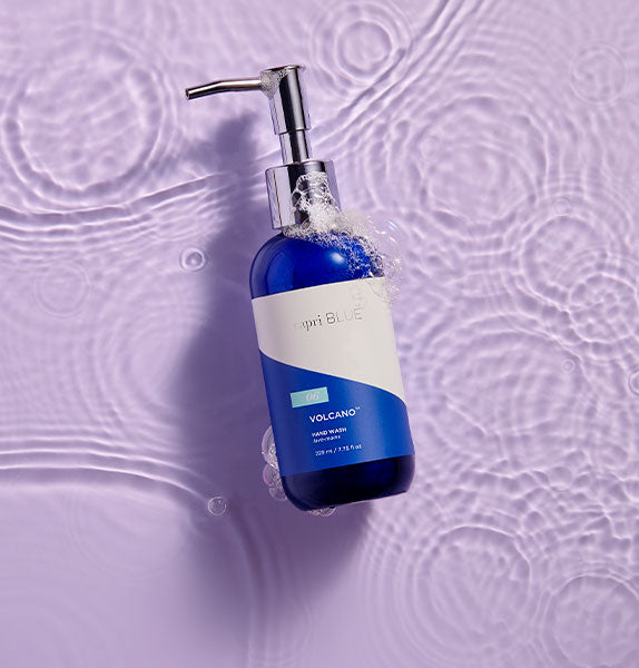 Blue bottle of hand wash with pump on a textured purple background