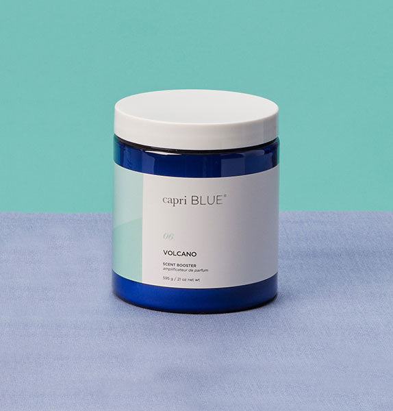 Capri Blue Volcano candle on a blue surface with a teal background