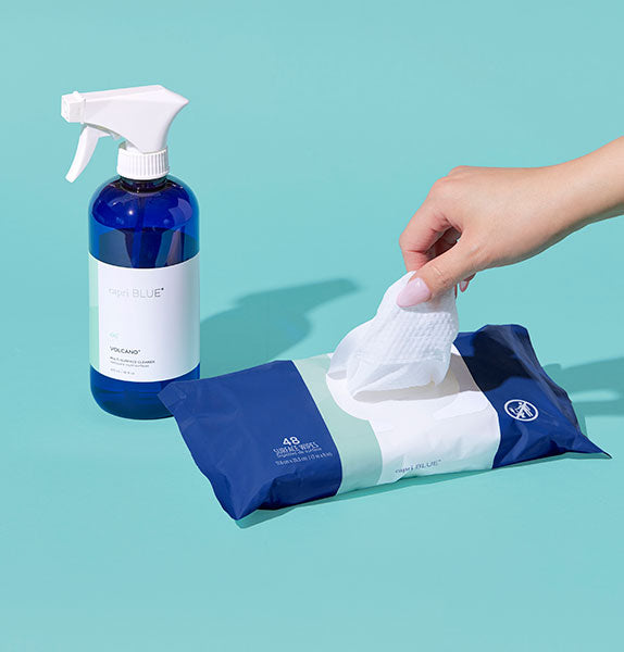 Cleaning product set with spray bottle and wipes on a light blue background