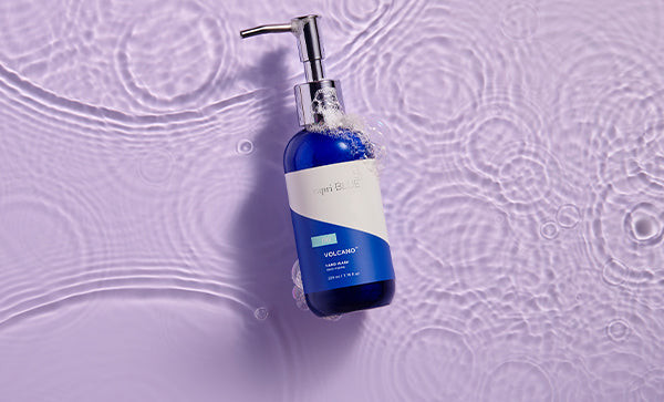 Blue dispenser bottle with pump on a textured purple background