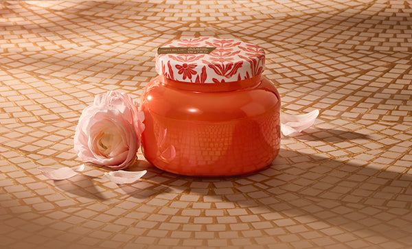 Coral-colored jar with a decorative lid on a textured surface