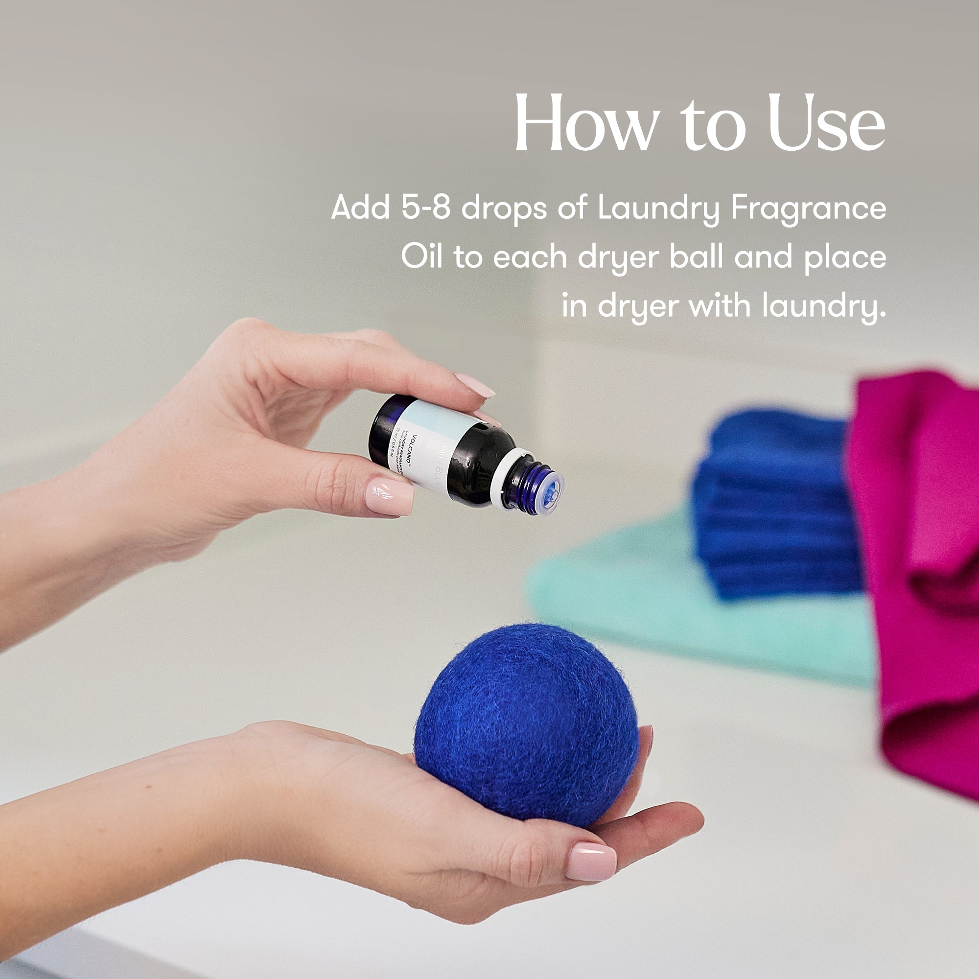 Hand holding a blue dryer ball with a bottle of fragrance oil, text on how to use laundry fragrance oil.