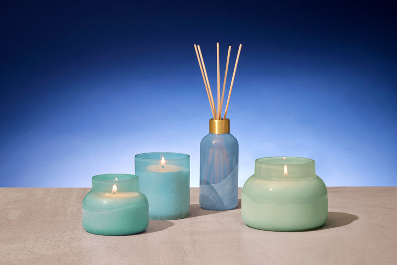 Set of teal candles and a diffuser on a blue background