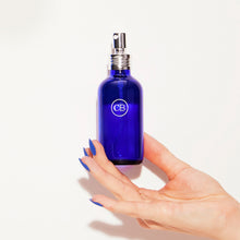 Hand holding a blue room spray on a white background
