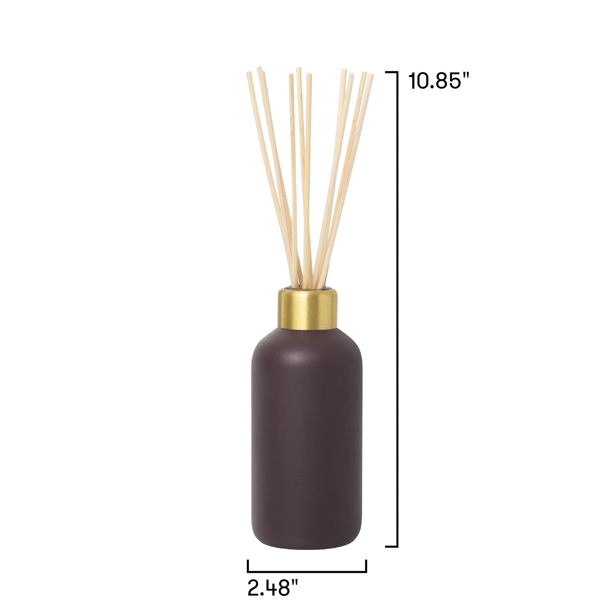 A reed diffuser bottle in dark brown with a gold collar and natural wood reeds, shown with dimension lines indicating a height of 10.85 inches and a base width of 2.