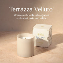 Terrazza Velluto Coconut Santal scented candle in a matte cream-colored ceramic jar, shown next to its white packaging box with gold and blue lettering on a warm beige stone-textured surface.