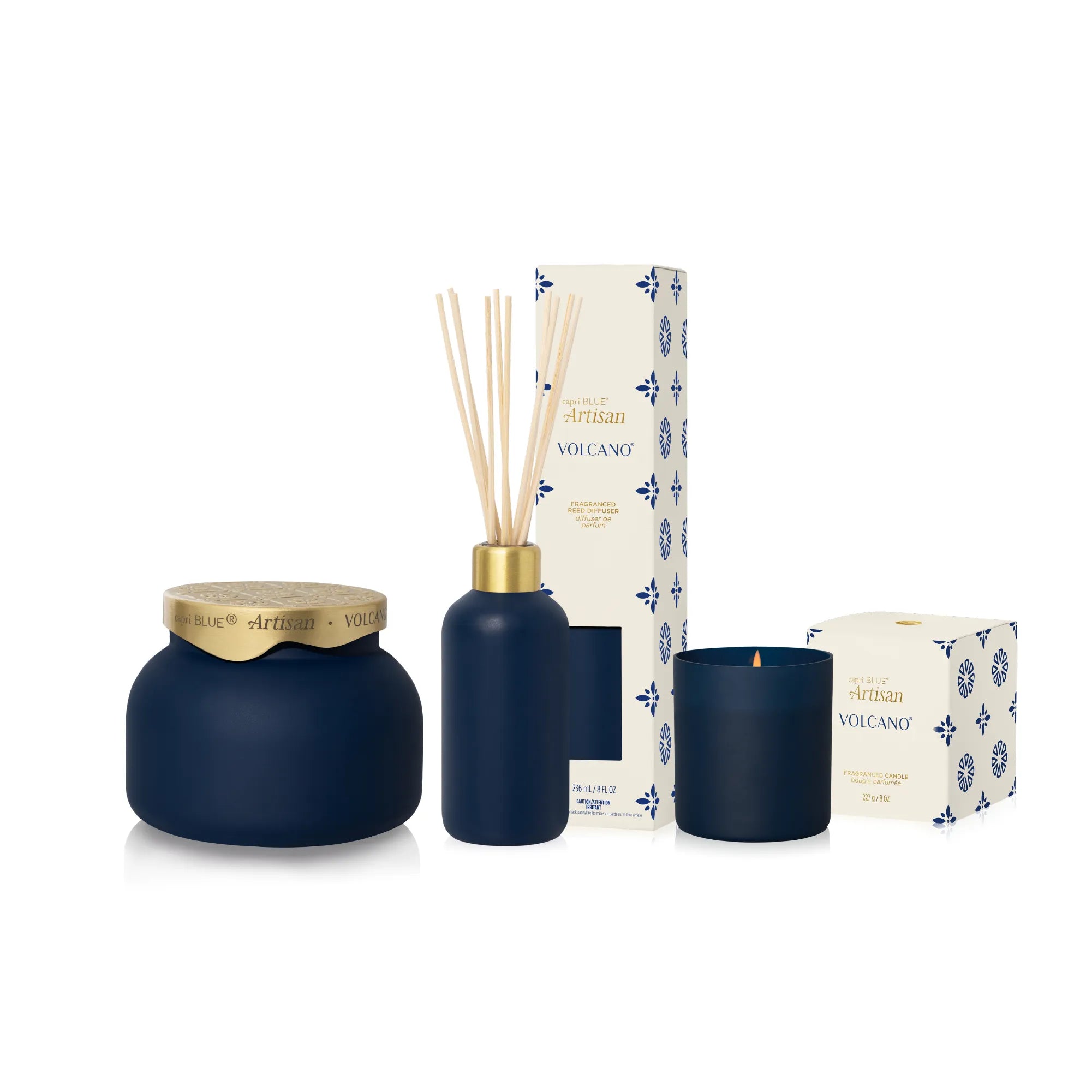 A reed diffuser and candle set in a matching matte navy blue color, accented with gold metal details. The set includes a round jar with a gold lid, a reed diffuser bottle with natural reeds, a navy blue candle, and their patterned cream packaging boxes.