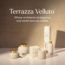 Terrazza Velluto home fragrance set including a reed diffuser, candle, jar, and box, styled on a white surface against a textured beige wall with warm lighting.