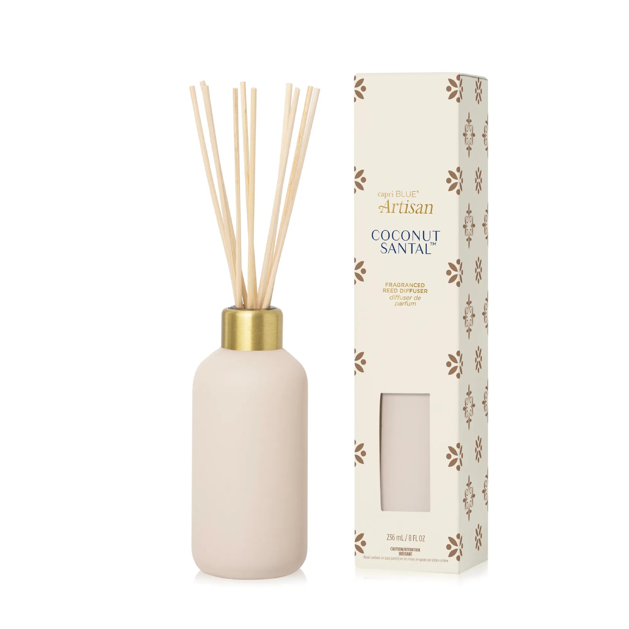 A reed diffuser bottle with natural reed sticks and a gold collar, shown next to its cream-colored packaging box with brown floral patterns. The brand 'Artisan' is visible on the box.