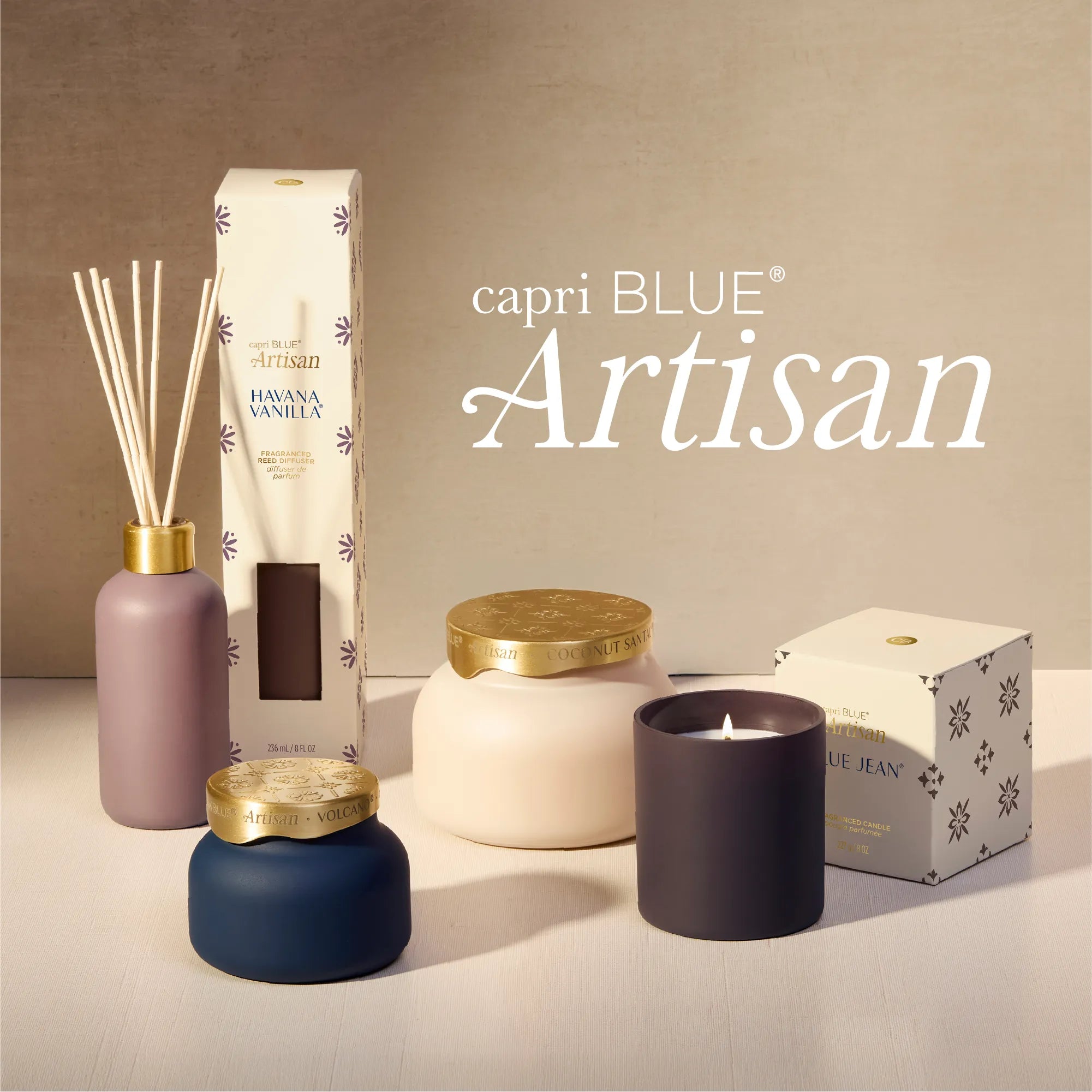 A curated product lineup from capri BLUE Artisan featuring a reed diffuser, a candle, a jar candle, and boxes, styled on a light surface against a warm beige background with the brand name 'capri BLUE Artisan' displayed in white text.