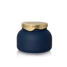 A dark navy blue jar with a textured gold lid, featuring the brand name 'In Blue' and product line 'Artisan Volcano' printed on the gold band.