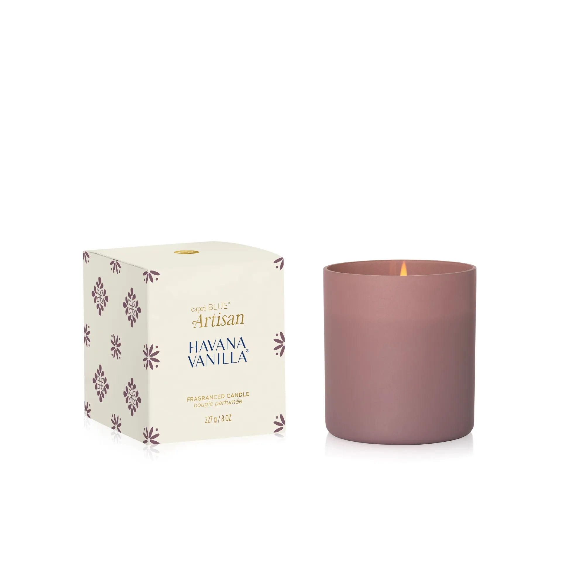 A matte dusty rose glass candle next to its cream-colored packaging box with purple floral patterns. The box is labeled 'Artisan Havana Vanilla' and features a small gold logo at the top.