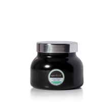 A black jar candle with a shiny silver lid and a circular label reading 'Capri Blue Coconut Scent' on a clean white background.