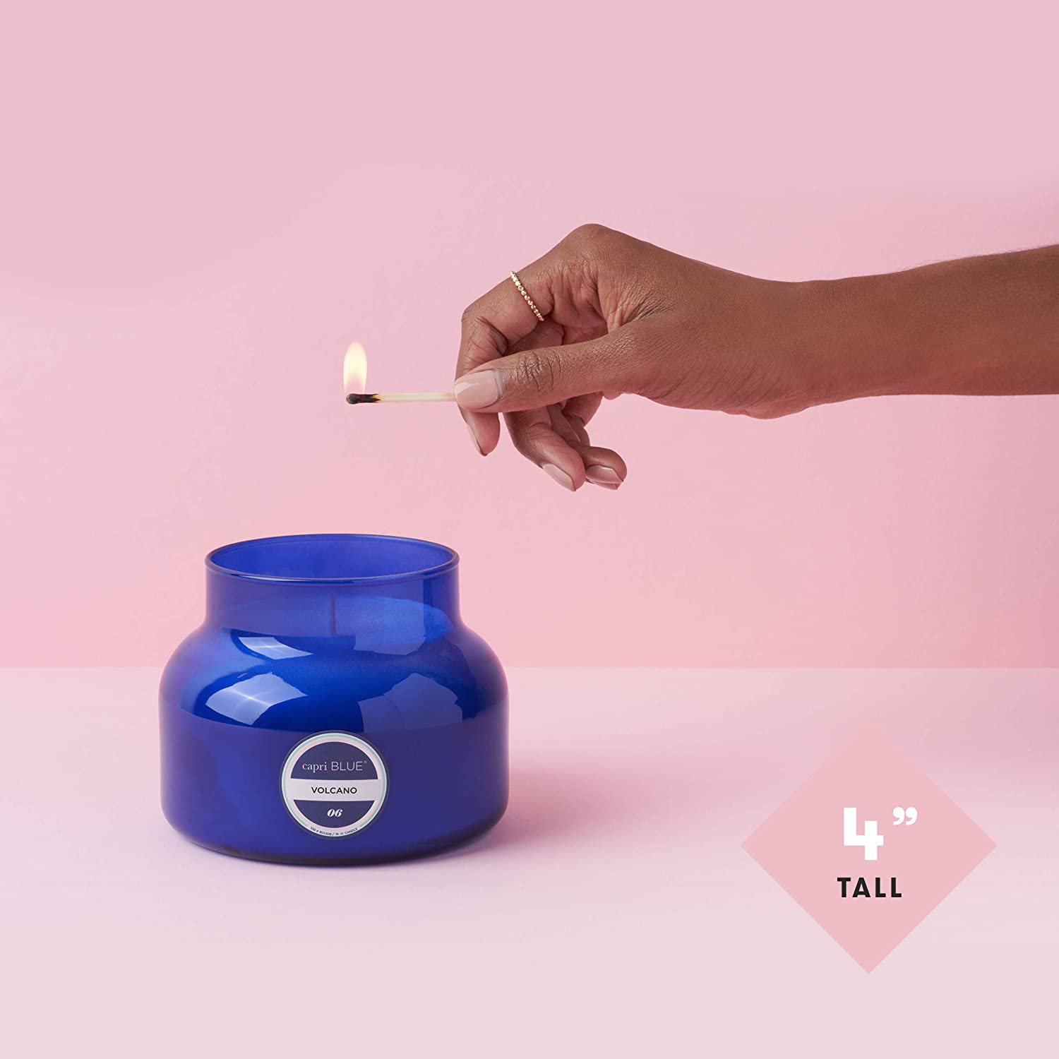 Hand lighting a blue candle with a pink background