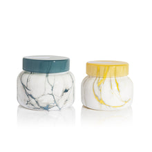 Two marble-patterned jars with colored lids on a white background