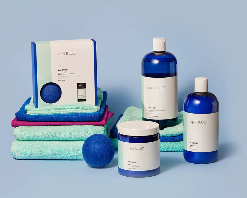 Collection of blue and green bath products including bottles, towels, and a ball on a light blue background.
